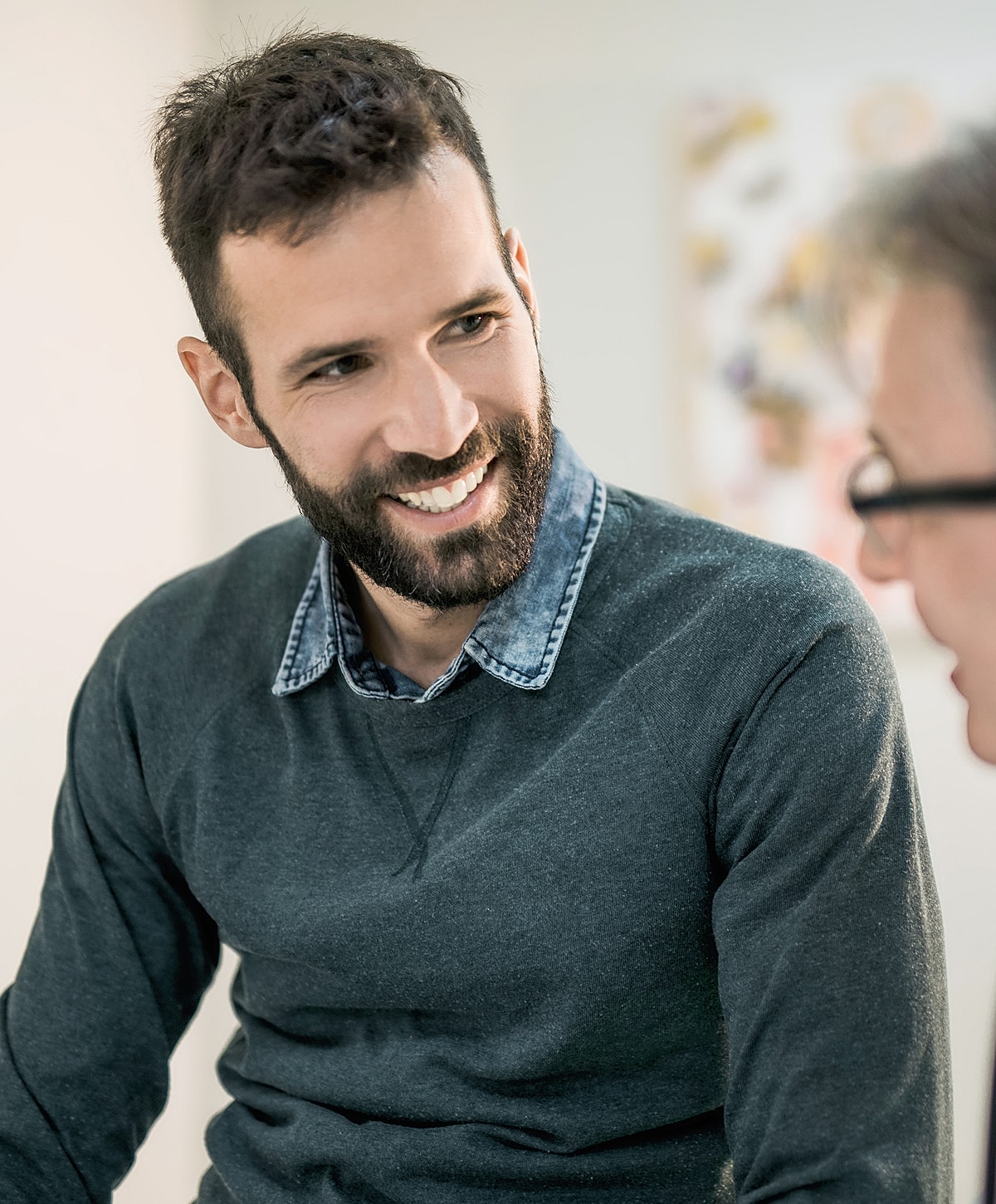 Smiling man engaging in conversation indoors.