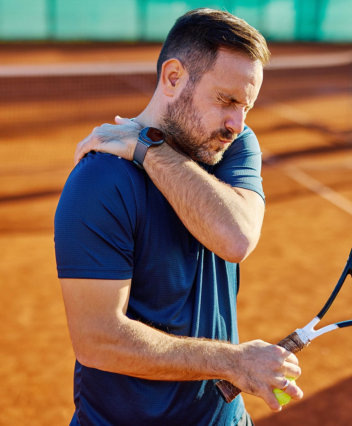 Man with shoulder pain on tennis court.