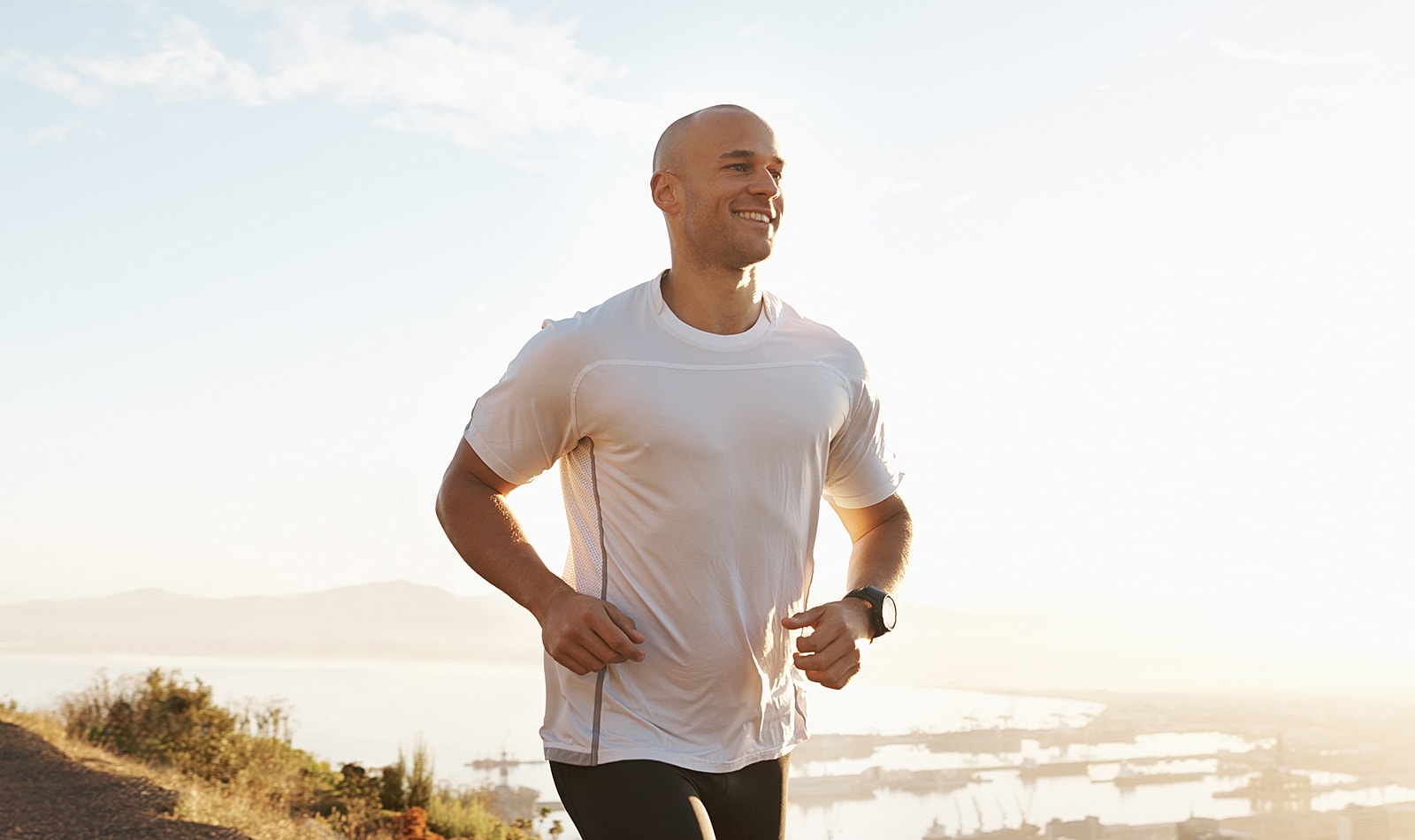 Man jogging outdoors with a scenic background.