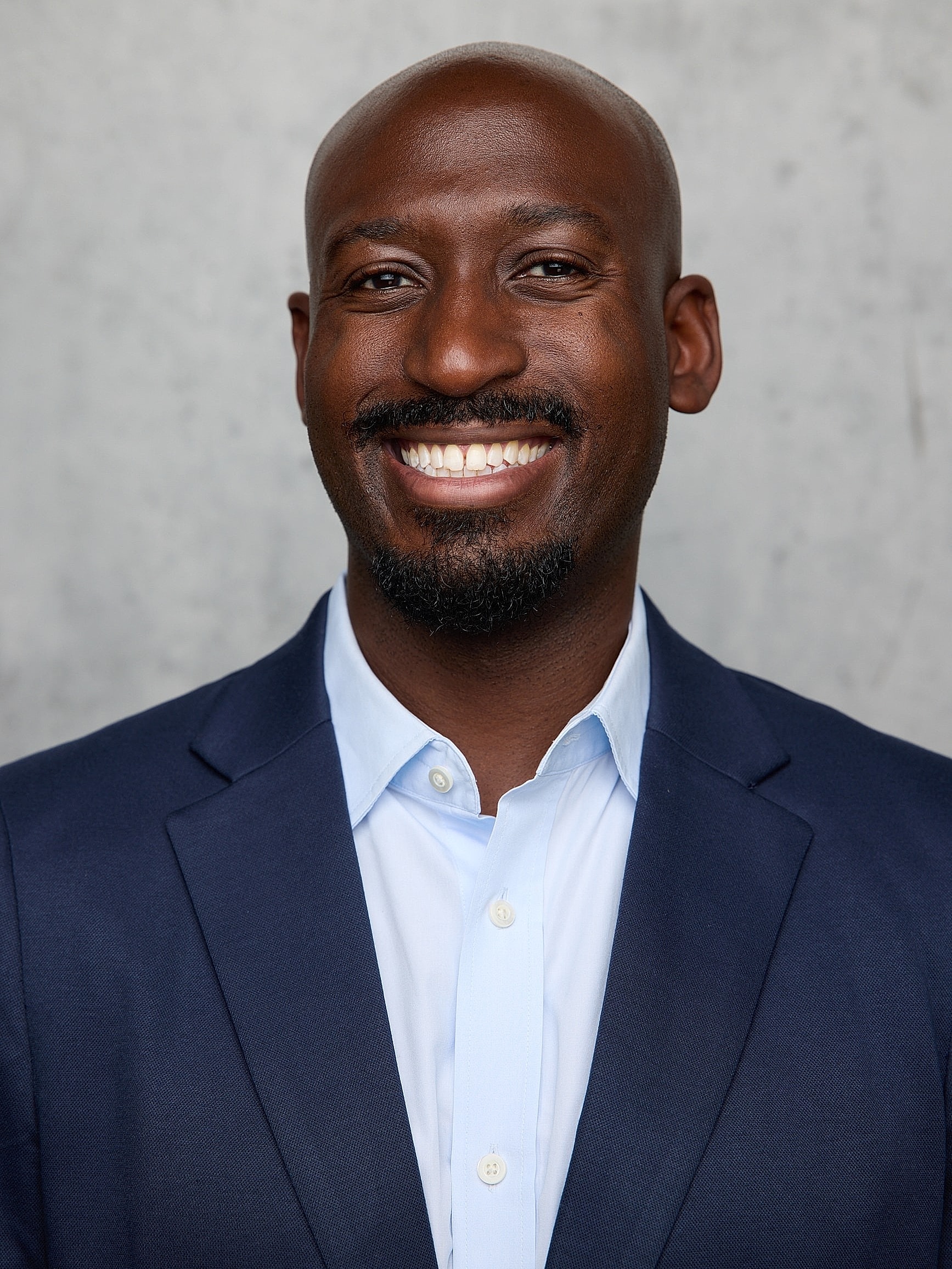 Smiling man in blue suit with red tie.