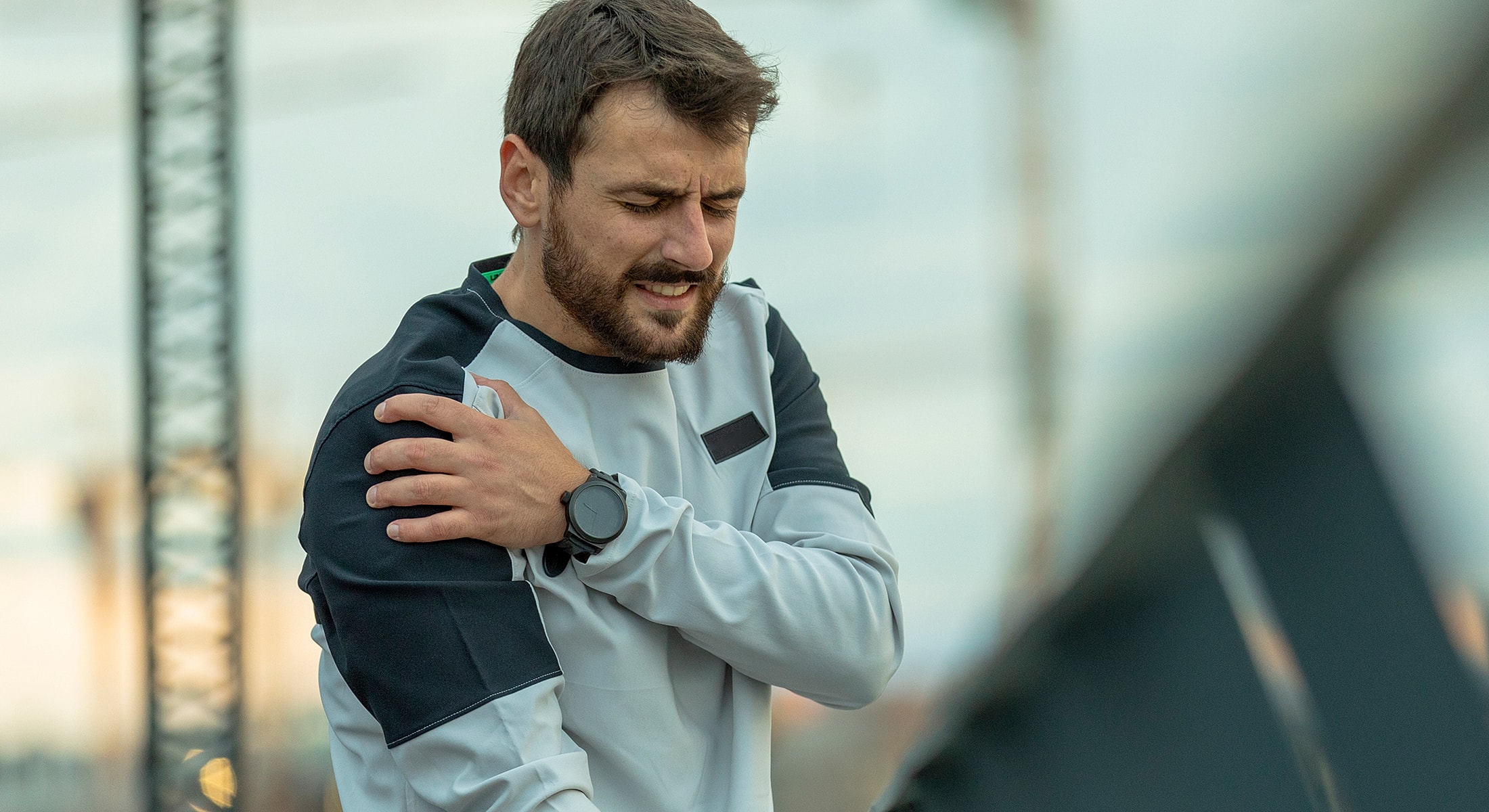 Man experiencing shoulder pain outdoors.